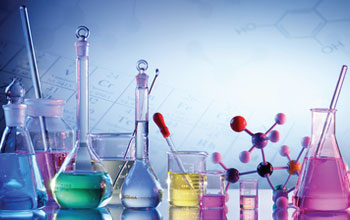 9 flasks with different colored liquids and a model atom on a desk 