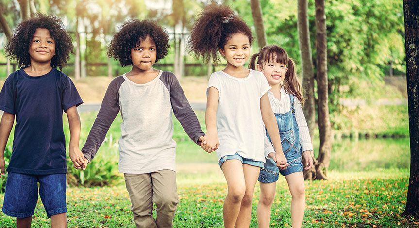4 happy kids holding hands in the outdoors