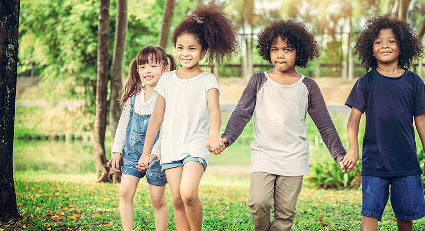 4 happy kids holding hands in the outdoors