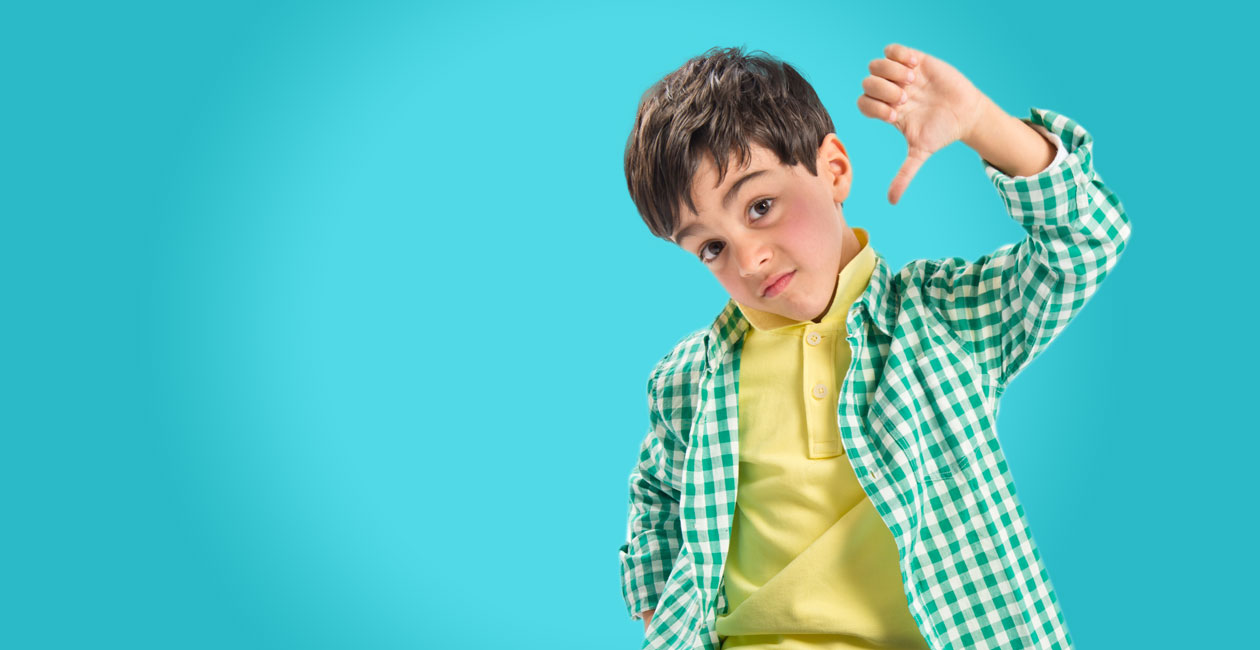Boy in green plaid shirt with his thumb pointing down